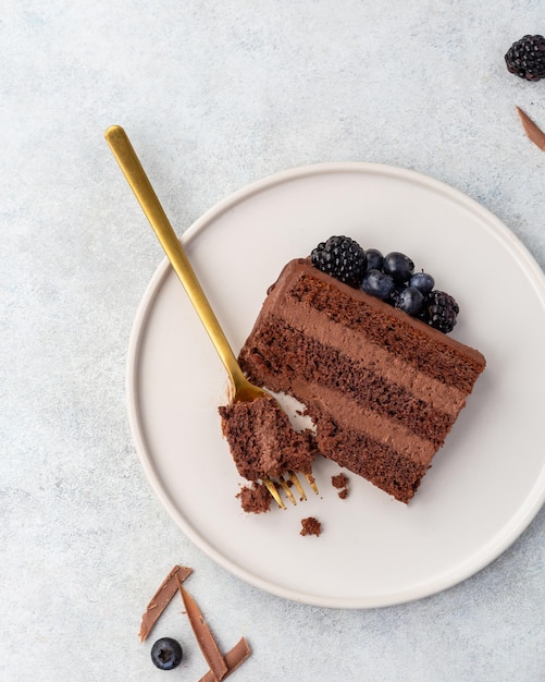 A piece of Chocolate cake with fresh berries and sour cream on a white background Top view