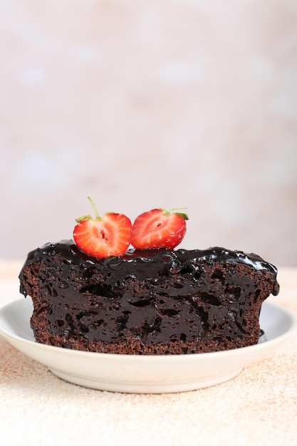 Piece of chocolate sponge cake with strawberry on beige textured table