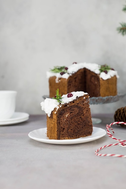 A piece of christmas cake on plate on grey table with cup of\
tea and christmas cake on the glass stand