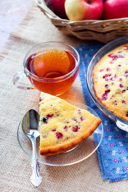 Piece of cowberry pie on glass plate and cup of tea