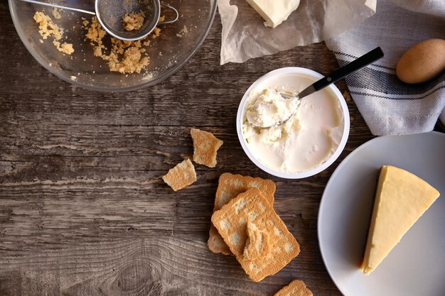 Piece of delicious cheese cake with ingredients on kitchen table