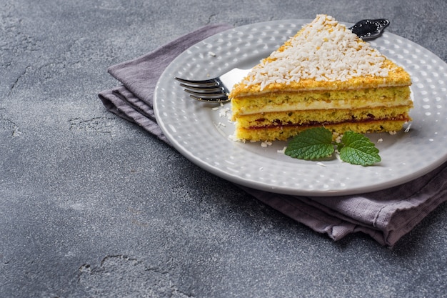 Piece of delicious puff cake with butter cream and berry jam on a plate with mint