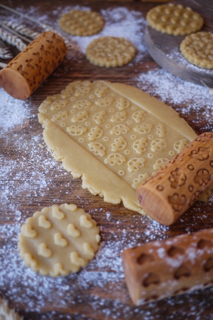 A piece of dough with a print of children's cars. Wooden rolling pins for cookies