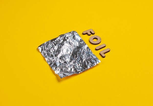 Piece of foil and word foil isolated on yellow