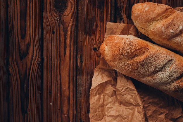 A piece of french baguette on the craft paper and dark wooden background