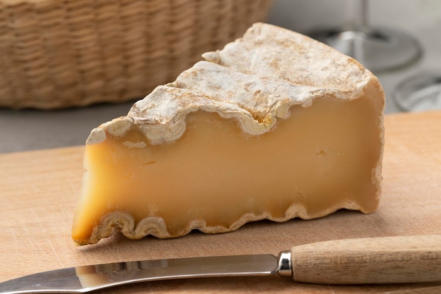 Piece of French Mountain Abbey cheese on a cutting board close up