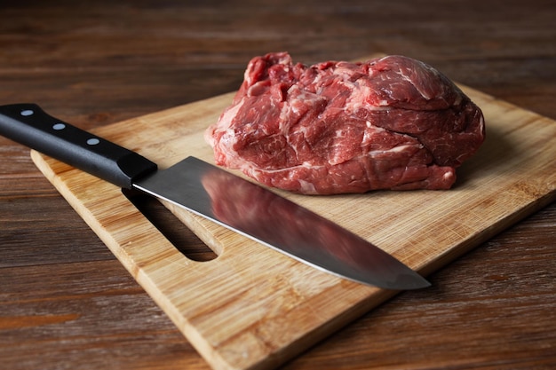 A piece of fresh beef and a knife on a cutting board Room for text High quality photo