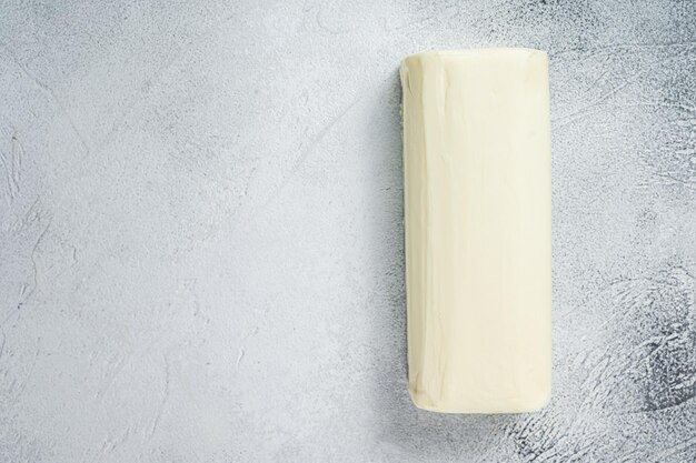 Piece of fresh butter for breakfast on kitchen table. White background. Top view. Copy space.