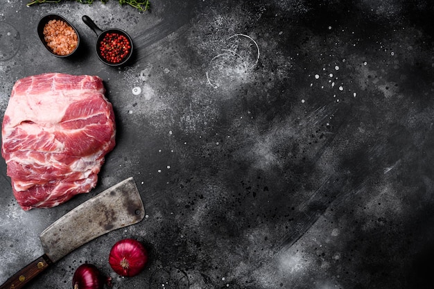 Piece of fresh raw pork from the neck set with ingredients and herbs with old butcher cleaver knife on black dark stone table background top view flat lay with copy space for text