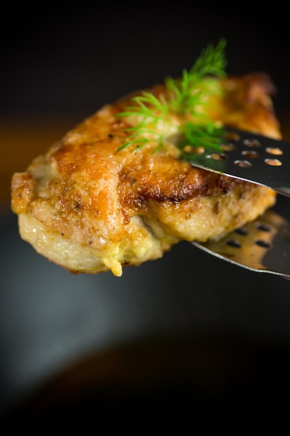 Foto un pezzo di filetto di pollo fritto con spezie su sfondo nero