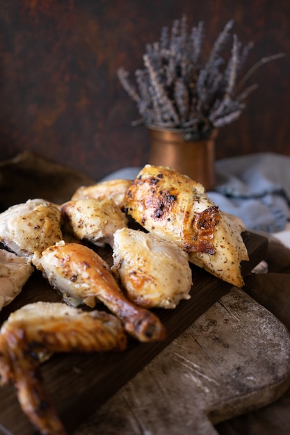 Piece of grilled chicken on dark wooden cutting board