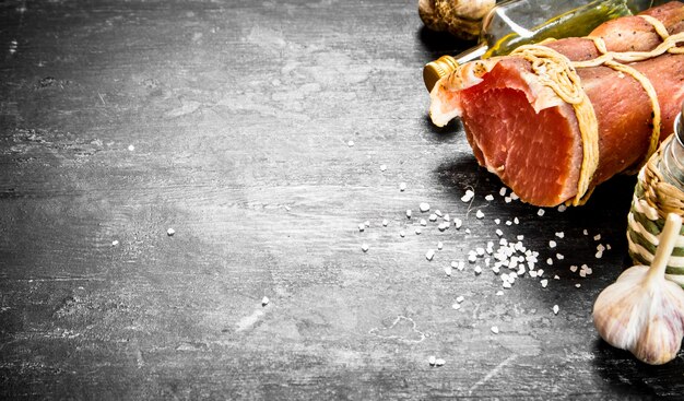 Foto pezzo di prosciutto con aglio, sale e olio d'oliva.