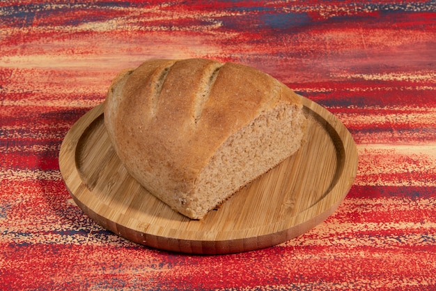 Piece of homemade bread cut on a bamboo tray on a rustic table