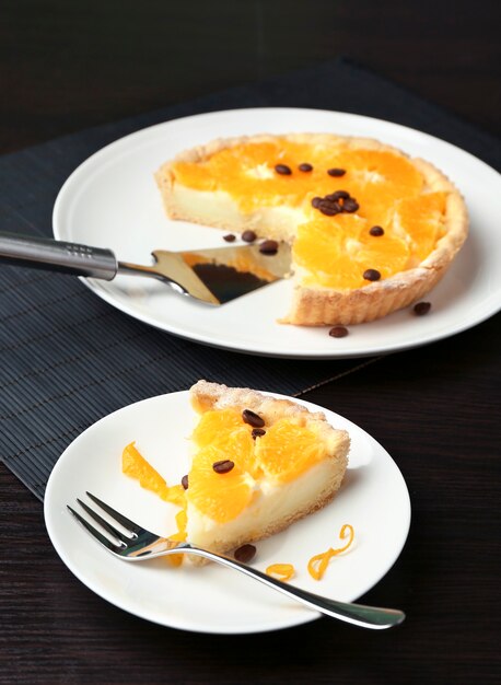 Piece of homemade orange tart on plate, on color wooden surface