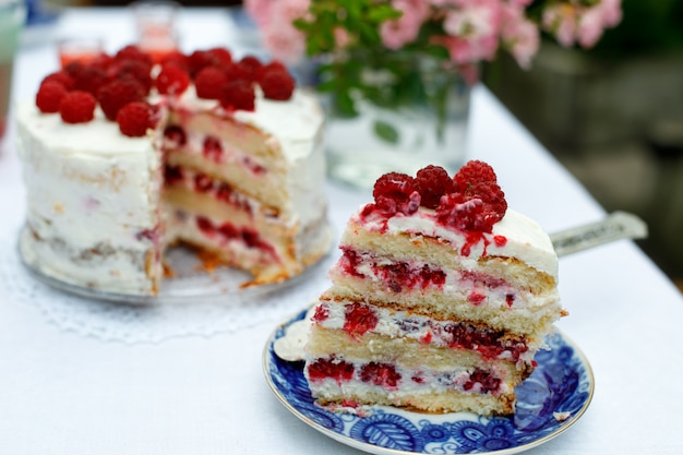 A piece of homemade raspberry cake on a table in a summer garden. Selective focus