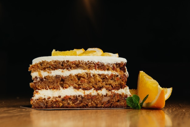 Piece of homemade tasty carrot sponge cake with pastry cream on wooden table