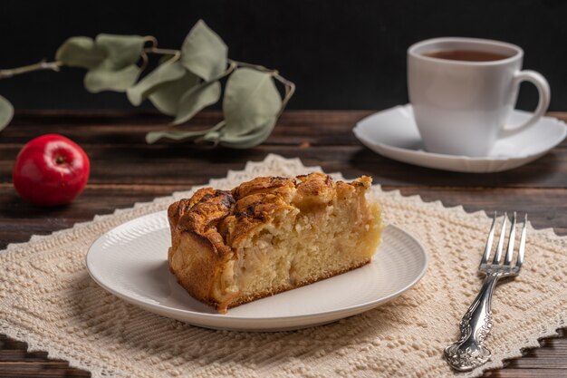 Piece of homemade traditional cornish apple pie on a white plate with a fork on a napkin