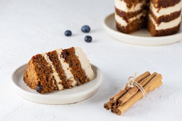 Piece of homemade vegan carrot cake with coconut cream and nuts on a plate