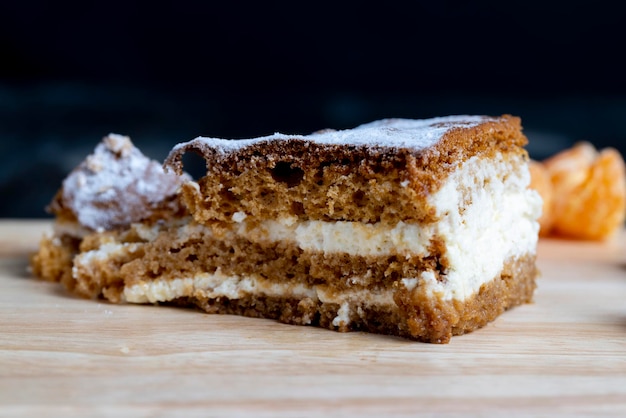 Un pezzo di torta al miele con crema alla vaniglia e mandarini agli agrumi