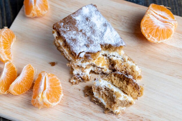 A piece of honey cake with vanilla cream and citrus tangerines