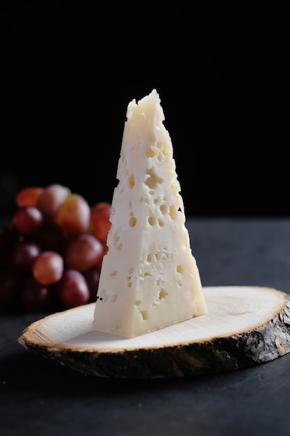 Piece of jarlsberg cheese with grapes on a wooden plate