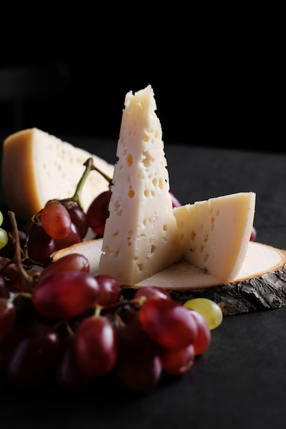 Piece of jarlsberg cheese with grapes on a wooden plate