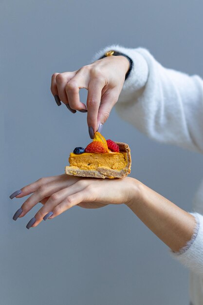 A piece of mango cheesecake on the hand of a girl with the delivery of proper nutrition