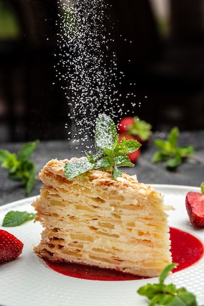 Photo piece of napoleon cake. creamy vanilla swith cream, apples and strawberry jam decorated mint