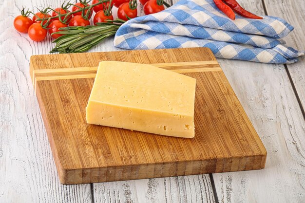 Piece of natural organic cheese over board served rosemary