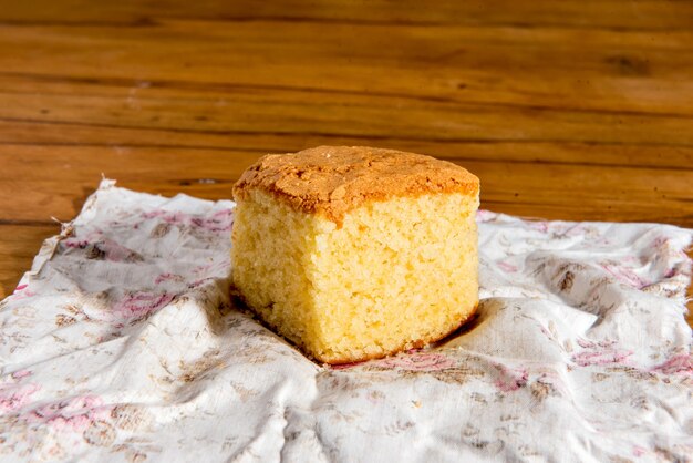 Piece of orange muffin on top of cloth.