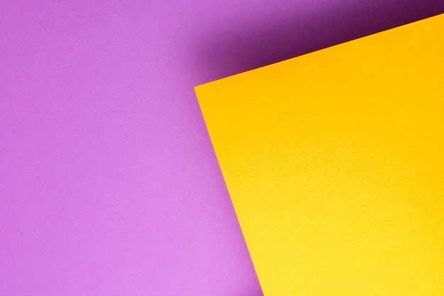 A piece of orange paper hovers over a purple background. Sheet cast a shadow.