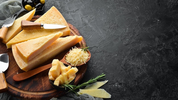パルメザンチーズとチーズナイフのかけら石の背景に伝統的なイタリアのチーズ上面図テキスト用の空きスペース