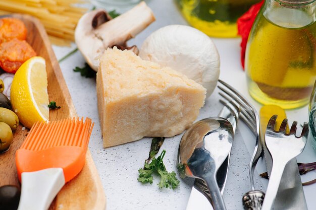 Piece of parmesan cheese surrounded with oil vegetables and cutlery