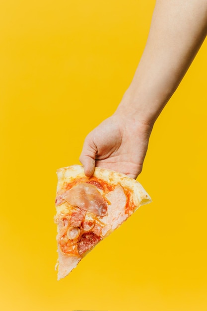 Piece of pizza in hand Studio photo on a colored background copy space