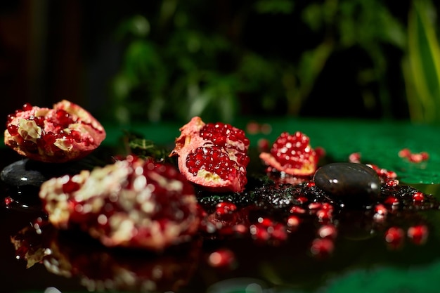Piece of pomegranate and whole fruits on black and green background