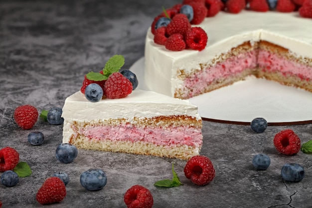 A piece of raspberry mint cake decorated with fresh raspberry and mint leaves