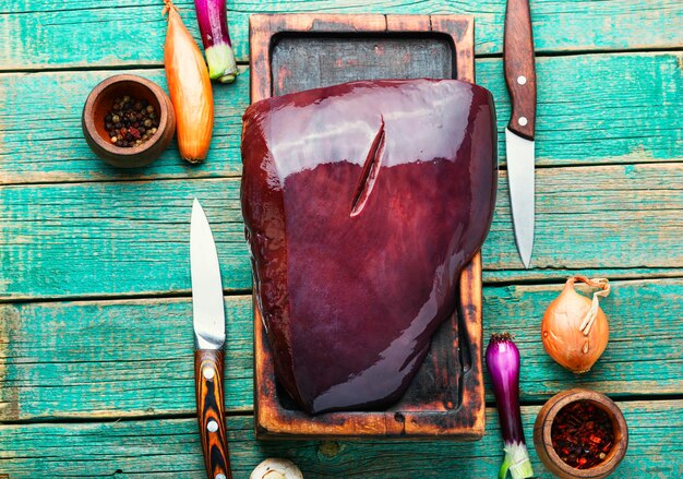 Photo piece of raw beef liver on the kitchen board