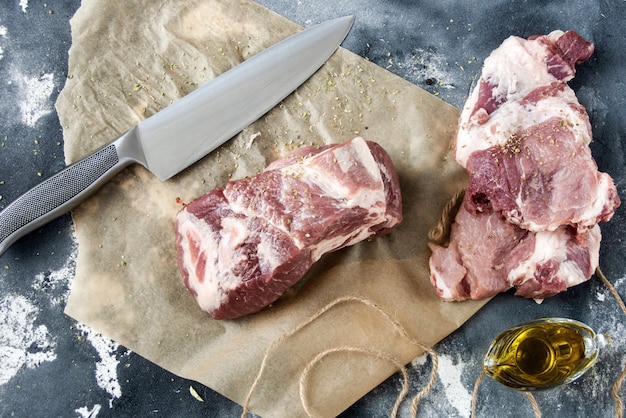 Piece of raw meat on the table, knife, top view