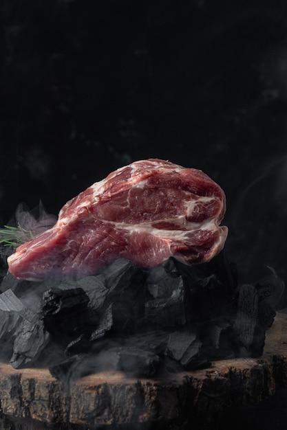 A piece of raw pork on the coals closeup