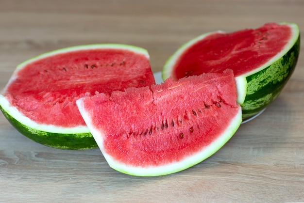 a piece of red juicy ripe watermelon on the background of cut watermelon on the table