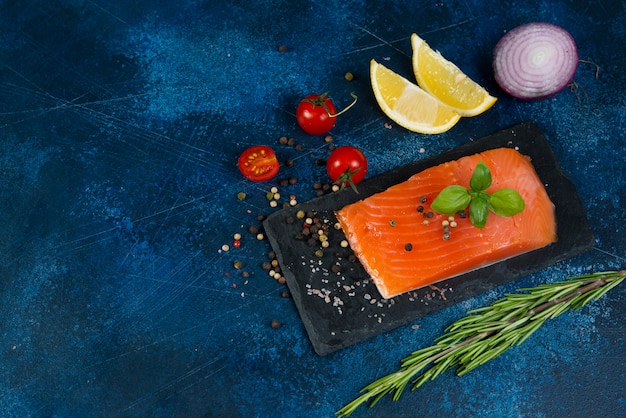 A piece of red salted fish lies on a coal Board with spices.