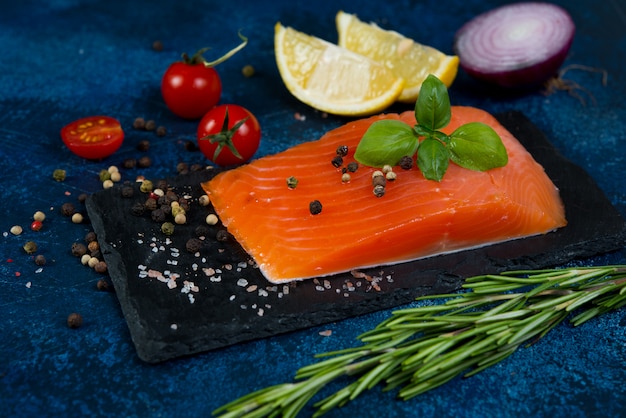 A piece of red salted fish lies on a coal Board with spices.