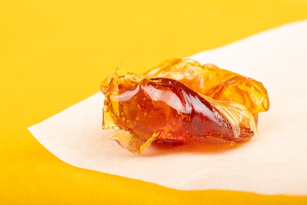 Piece of resin cannabis concentrate on yellow background medical marijuana extract.