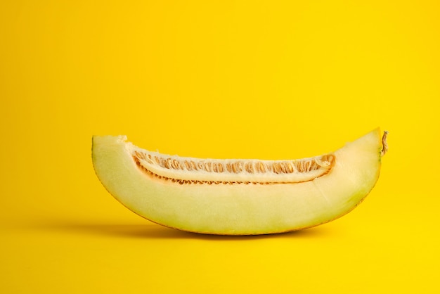 Piece of ripe melon with seeds on yellow 