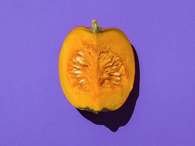 A piece of ripe pumpkin in bright light on a purple background. A delicious and healthy vegetable.