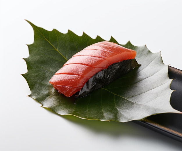 A piece of salmon sits on a leaf that is on a white table.