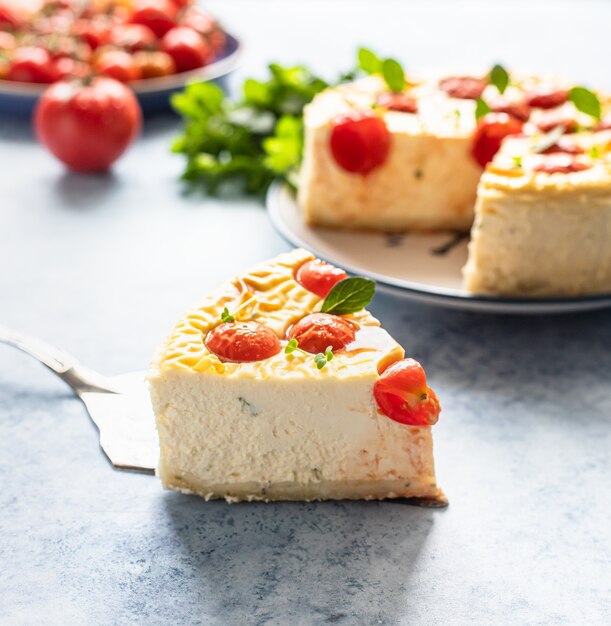 Piece of savoury tomato cheesecake with herbs decorated mint, blue concrete background.