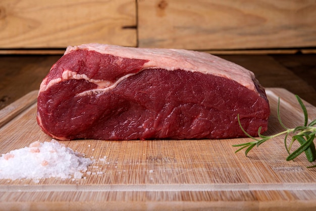 Photo piece of sirloin rosemary and salt on bamboo cutting board