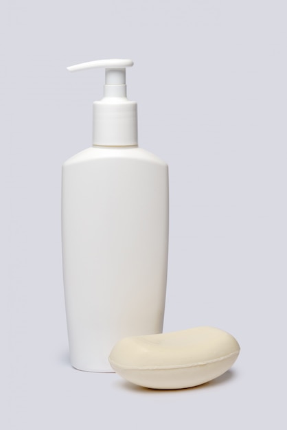 piece of soap and bottle of liquid soap over light grey backgound with clipping path