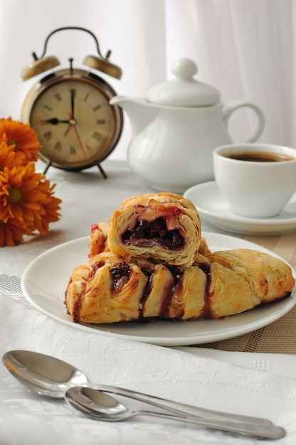 A piece of strudel with cherries with a morning cup of coffee